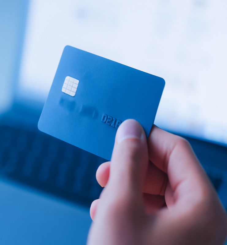 Person holding a blue credit card near a laptop, representing secure online payments and digital commerce.